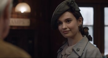 Movie still from “The Guernsey Literary and Potato Peel Pie Society” (2018), directed by Mike Newell – A young woman wearing a hat and a coat; Close Up shot, Over the shoulder angle