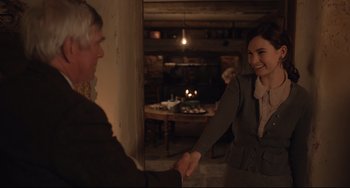 Movie still from “The Guernsey Literary and Potato Peel Pie Society” (2018), directed by Mike Newell – Two people are shaking hands in a room; Medium shot, Over the shoulder angle