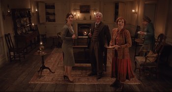 Movie still from “The Guernsey Literary and Potato Peel Pie Society” (2018), directed by Mike Newell – A group of people standing in front of a fire place; Wide shot, High angle