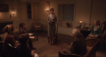 Movie still from “The Guernsey Literary and Potato Peel Pie Society” (2018), directed by Mike Newell – A group of people sitting in a living room; Wide shot, High angle
