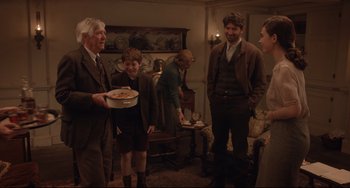 Movie still from “The Guernsey Literary and Potato Peel Pie Society” (2018), directed by Mike Newell – A group of people standing in a living room; Medium shot, Over the shoulder angle