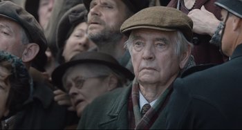 Movie still from “The Guernsey Literary and Potato Peel Pie Society” (2018), directed by Mike Newell – An older man wearing a hat and a coat; Close Up shot, Low angle