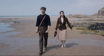 Movie still from “The Guernsey Literary and Potato Peel Pie Society” (2018), directed by Mike Newell – A man and a woman walking on the beach; Wide shot, High angle