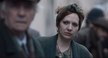 Movie still from “The Guernsey Literary and Potato Peel Pie Society” (2018), directed by Mike Newell – A person wearing a head scarf; Close Up shot, Over the shoulder angle