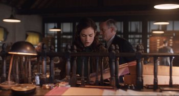 Movie still from “The Guernsey Literary and Potato Peel Pie Society” (2018), directed by Mike Newell – A woman sitting at a table looking down at the table; Medium shot, Over the shoulder angle