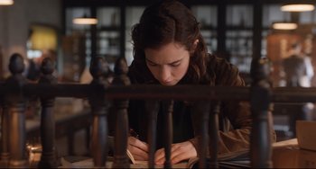 Movie still from “The Guernsey Literary and Potato Peel Pie Society” (2018), directed by Mike Newell – A woman writing on a piece of paper in a room; Medium shot, High angle