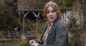 Movie still from “The Guernsey Literary and Potato Peel Pie Society” (2018), directed by Mike Newell – A woman holding a plant in her hands; Medium shot, Over the shoulder angle
