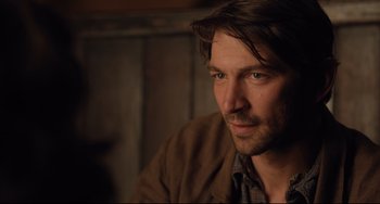 Movie still from “The Guernsey Literary and Potato Peel Pie Society” (2018), directed by Mike Newell – A person wearing a brown jacket; Close Up shot, Over the shoulder angle