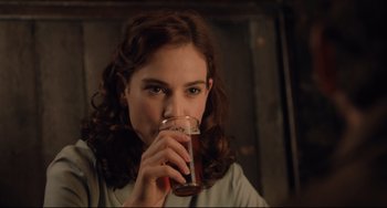 Movie still from “The Guernsey Literary and Potato Peel Pie Society” (2018), directed by Mike Newell – A woman drinking a glass of beer from a mug; Close Up shot, Over the shoulder angle