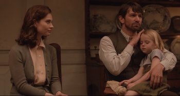 Movie still from “The Guernsey Literary and Potato Peel Pie Society” (2018), directed by Mike Newell – A man and a woman sitting next to each other in a room; Medium shot, Over the shoulder angle