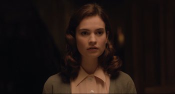 Movie still from “The Guernsey Literary and Potato Peel Pie Society” (2018), directed by Mike Newell – A young woman in a brown jacket and a pink shirt; Close Up shot, Over the shoulder angle
