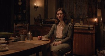 Movie still from “The Guernsey Literary and Potato Peel Pie Society” (2018), directed by Mike Newell – A woman sitting at a table with a cup of coffee; Medium shot, Over the shoulder angle