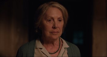 Movie still from “The Guernsey Literary and Potato Peel Pie Society” (2018), directed by Mike Newell – An older woman wearing a green necklace and a white shirt; Close Up shot, Over the shoulder angle