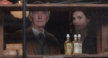 Movie still from “The Guernsey Literary and Potato Peel Pie Society” (2018), directed by Mike Newell – An older man and a young woman are looking through a shelf; Close Up shot, Over the shoulder angle