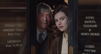 Movie still from “The Guernsey Literary and Potato Peel Pie Society” (2018), directed by Mike Newell – A man and a woman standing next to each other; Medium shot, Over the shoulder angle