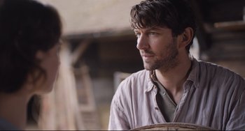 Movie still from “The Guernsey Literary and Potato Peel Pie Society” (2018), directed by Mike Newell – A man in a white shirt is looking to his left; Close Up shot, Over the shoulder angle