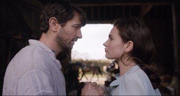 Movie still from “The Guernsey Literary and Potato Peel Pie Society” (2018), directed by Mike Newell – A man and a woman holding hands in front of horses; Close Up shot, Over the shoulder angle