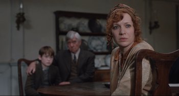 Movie still from “The Guernsey Literary and Potato Peel Pie Society” (2018), directed by Mike Newell – A woman sitting at a table with two men and a boy; Close Up shot, Over the shoulder angle