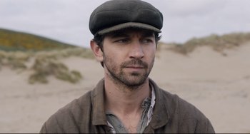 Movie still from “The Guernsey Literary and Potato Peel Pie Society” (2018), directed by Mike Newell – A person wearing a hat; Close Up shot, Over the shoulder angle