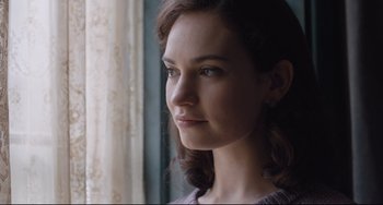 Movie still from “The Guernsey Literary and Potato Peel Pie Society” (2018), directed by Mike Newell – A person looking out of a window; Close Up shot, Over the shoulder angle