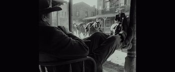 Movie still from “Once Upon a Time in Hollywood” (2019), directed by Quentin Tarantino – A man sitting in a chair in front of a group of horses; Wide shot, Low angle