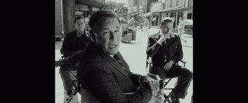 Movie still from “Once Upon a Time in Hollywood” (2019), directed by Quentin Tarantino – A black - and - white photo of a man sitting in a chair; Medium shot, Over the shoulder angle