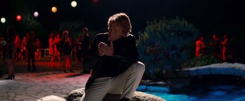 Movie still from “Once Upon a Time in Hollywood” (2019), directed by Quentin Tarantino – A man sitting on top of a rock at night; Medium shot, Low angle