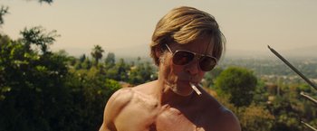 Movie still from “Once Upon a Time in Hollywood” (2019), directed by Quentin Tarantino – A shirtless man with sunglasses smoking a cigarette; Close Up shot, Low angle