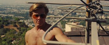 Movie still from “Once Upon a Time in Hollywood” (2019), directed by Quentin Tarantino – A shirtless man with sunglasses is on a balcony overlooking a city; Close Up shot, Low angle