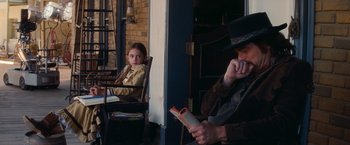 Movie still from “Once Upon a Time in Hollywood” (2019), directed by Quentin Tarantino – A man and a little girl sitting on a chair reading; Medium shot, Over the shoulder angle