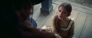 Movie still from “Once Upon a Time in Hollywood” (2019), directed by Quentin Tarantino – A young girl sitting on the ground holding a book; Close Up shot, Over the shoulder angle