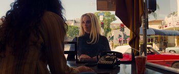 Movie still from “Once Upon a Time in Hollywood” (2019), directed by Quentin Tarantino – A woman sitting at a table talking to another woman; Medium shot, Over the shoulder angle