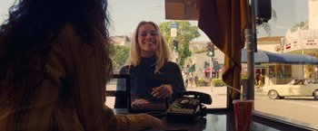 Movie still from “Once Upon a Time in Hollywood” (2019), directed by Quentin Tarantino – A woman sitting at a counter with a phone; Medium shot, Over the shoulder angle