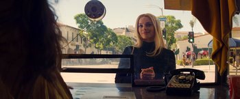 Movie still from “Once Upon a Time in Hollywood” (2019), directed by Quentin Tarantino – A woman sitting at a table in front of a window; Medium shot, Over the shoulder angle
