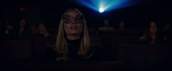 Movie still from “Once Upon a Time in Hollywood” (2019), directed by Quentin Tarantino – A woman with glasses sitting in front of a projection screen; Medium shot, Low angle