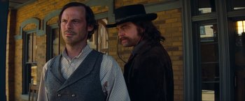 Movie still from “Once Upon a Time in Hollywood” (2019), directed by Quentin Tarantino – A man with long hair wearing a black hat; Medium shot, Over the shoulder angle