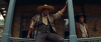 Movie still from “Once Upon a Time in Hollywood” (2019), directed by Quentin Tarantino – A man sitting on the steps of a building wearing a cowboy hat; Medium shot, Low angle