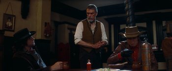 Movie still from “Once Upon a Time in Hollywood” (2019), directed by Quentin Tarantino – An older man standing in front of a group of people; Medium shot, Over the shoulder angle