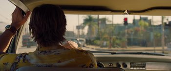 Movie still from “Once Upon a Time in Hollywood” (2019), directed by Quentin Tarantino – A woman sitting in the driver's seat of a car; Medium shot, Over the shoulder angle