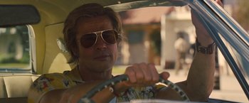 Movie still from “Once Upon a Time in Hollywood” (2019), directed by Quentin Tarantino – A man driving a car wearing sunglasses and holding the steering wheel; Close Up shot, Low angle