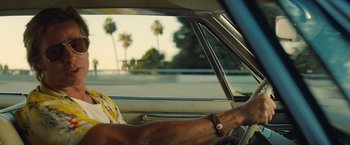 Movie still from “Once Upon a Time in Hollywood” (2019), directed by Quentin Tarantino – A man driving a car with a bunch of palm trees in the background; Close Up shot, Low angle