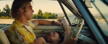 Movie still from “Once Upon a Time in Hollywood” (2019), directed by Quentin Tarantino – Two people in a car , one of which is holding the steering wheel; Medium shot, Low angle