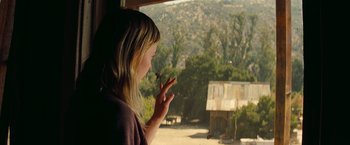 Movie still from “Once Upon a Time in Hollywood” (2019), directed by Quentin Tarantino – A woman standing in front of a window looking out at the trees; Close Up shot, Over the shoulder angle