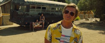 Movie still from “Once Upon a Time in Hollywood” (2019), directed by Quentin Tarantino – A man in a yellow shirt and a bus in the background; Medium shot, Over the shoulder angle