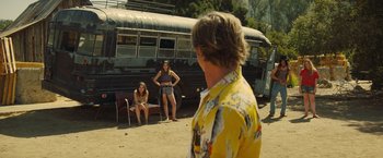 Movie still from “Once Upon a Time in Hollywood” (2019), directed by Quentin Tarantino – Two women and a man standing in front of an old bus; Wide shot, Over the shoulder angle