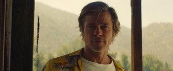 Movie still from “Once Upon a Time in Hollywood” (2019), directed by Quentin Tarantino – A man with long blonde hair wearing a yellow shirt; Close Up shot, Low angle