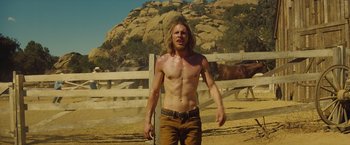 Movie still from “Once Upon a Time in Hollywood” (2019), directed by Quentin Tarantino – A man standing in the dirt near a fence with horses; Medium shot, Low angle