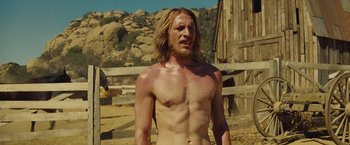 Movie still from “Once Upon a Time in Hollywood” (2019), directed by Quentin Tarantino – A man with long blonde hair stands in the dirt; Medium shot, Low angle