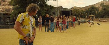 Movie still from “Once Upon a Time in Hollywood” (2019), directed by Quentin Tarantino – A group of young women standing in a row on a dirt field; Wide shot, Over the shoulder angle