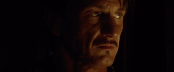 Movie still from “The Gunman” (2015), directed by Pierre Morel – A man's face in the dark; Close Up shot, Low angle